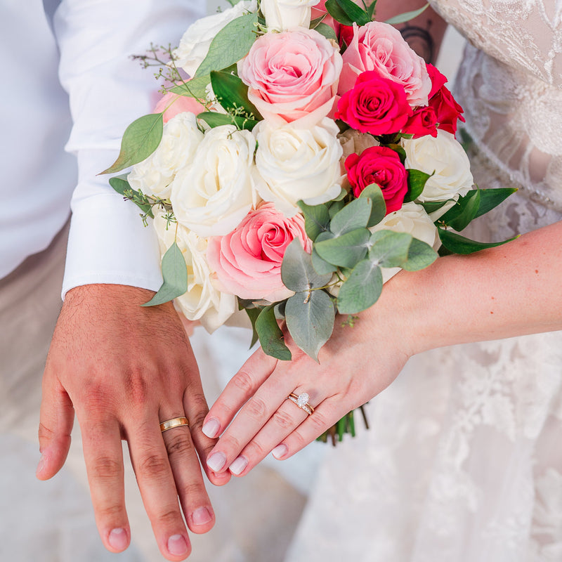Bride and groom holding hands with a colorful bouquet of flowers.