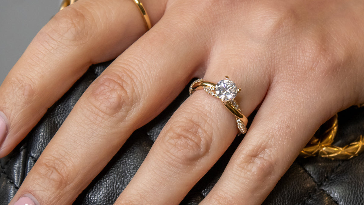 The Amelia twist engagement ring in yellow gold with a round cut diamond, worn on the hand, by Lisa Robin