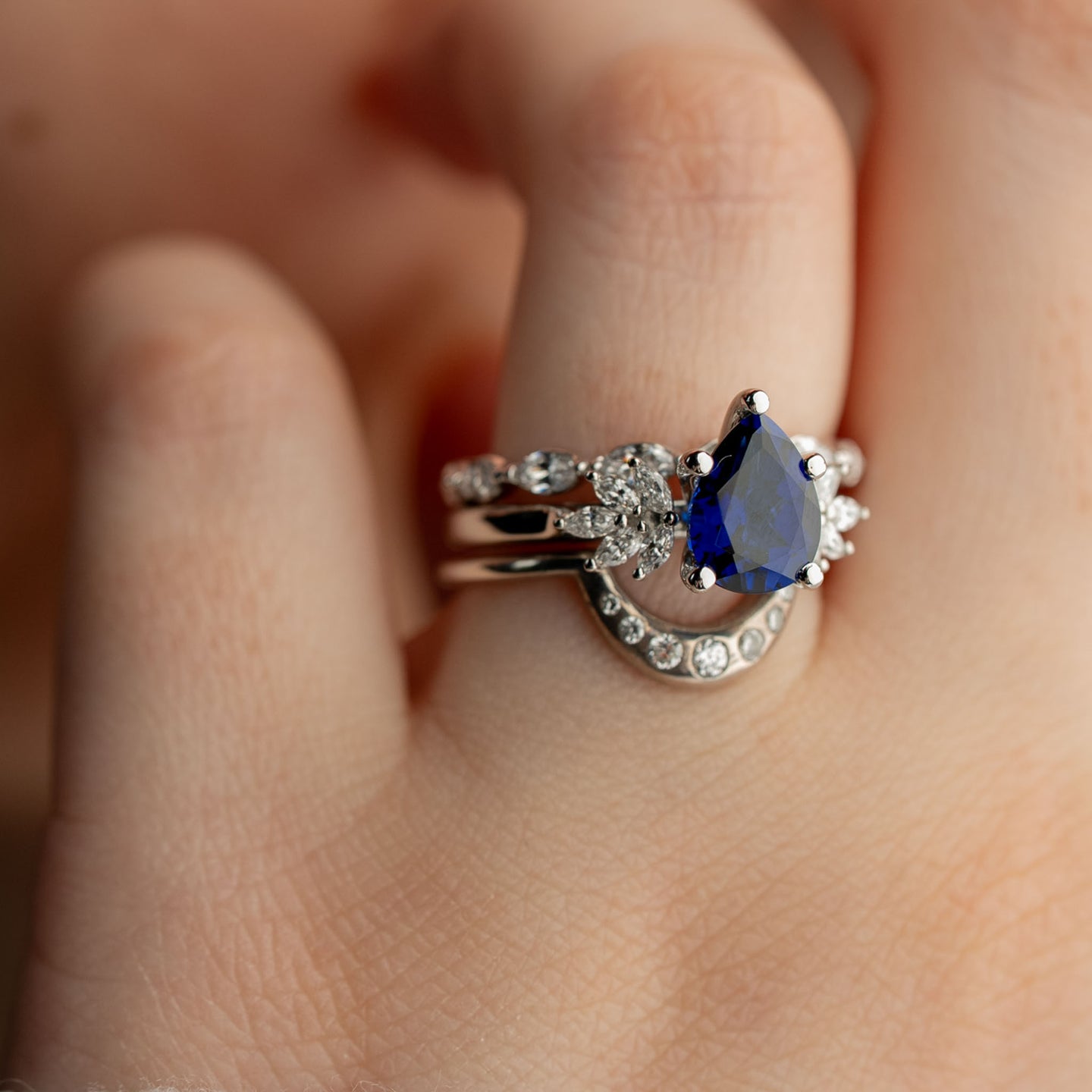 Anna blue sapphire 2 carat pear shaped engagement ring in white gold styled with the Valentina curved ring and the Finley marquise diamond wedding ring from Lisa Robin Jewelry