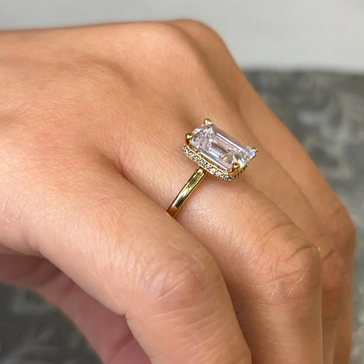 Hidden halo emerald cut diamond engagement ring on model by Lisa Robin