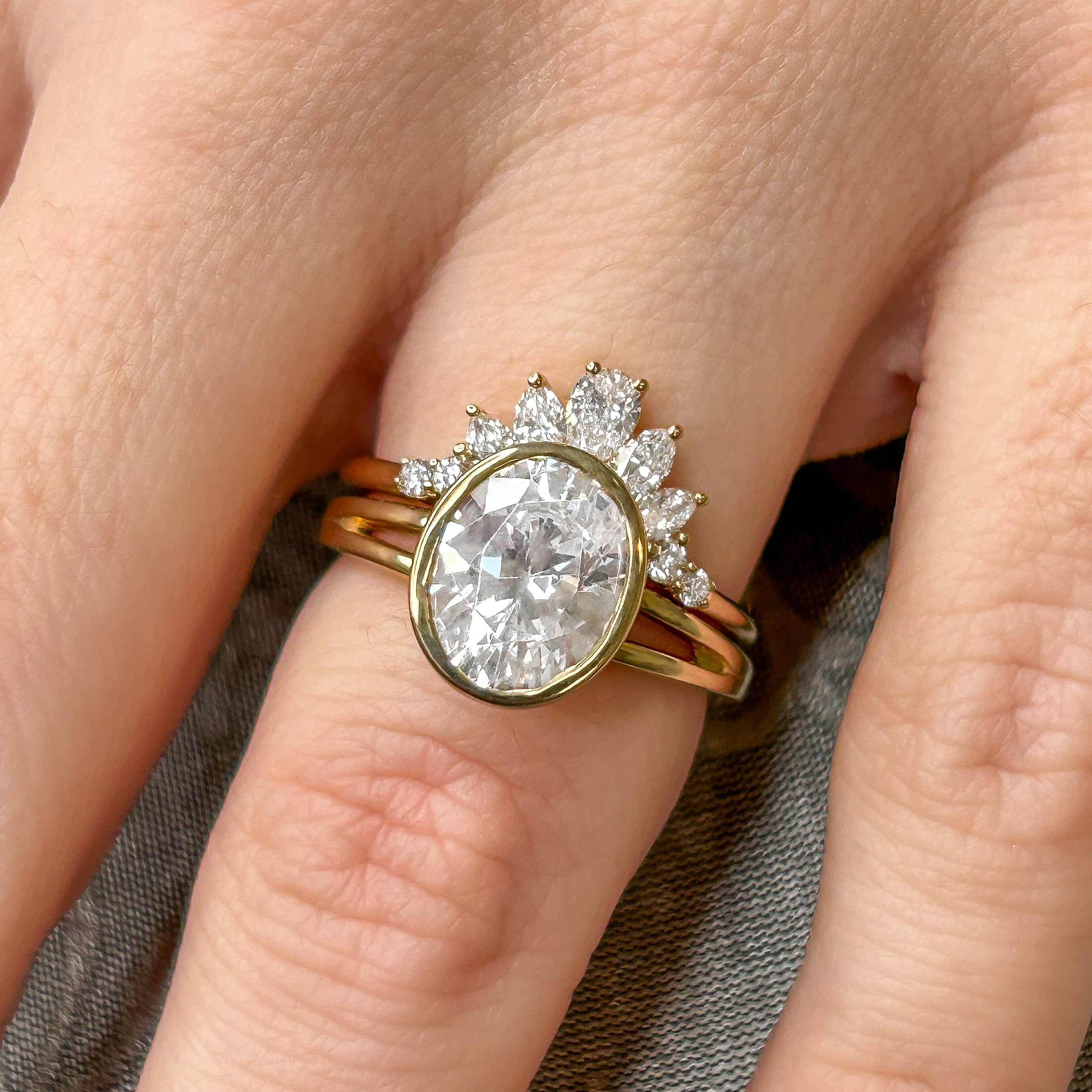 The Emery Bezel set Diamond Engagement Ring with oval cut diamond in yellow gold on model hand by Lisa Robin Jewelry