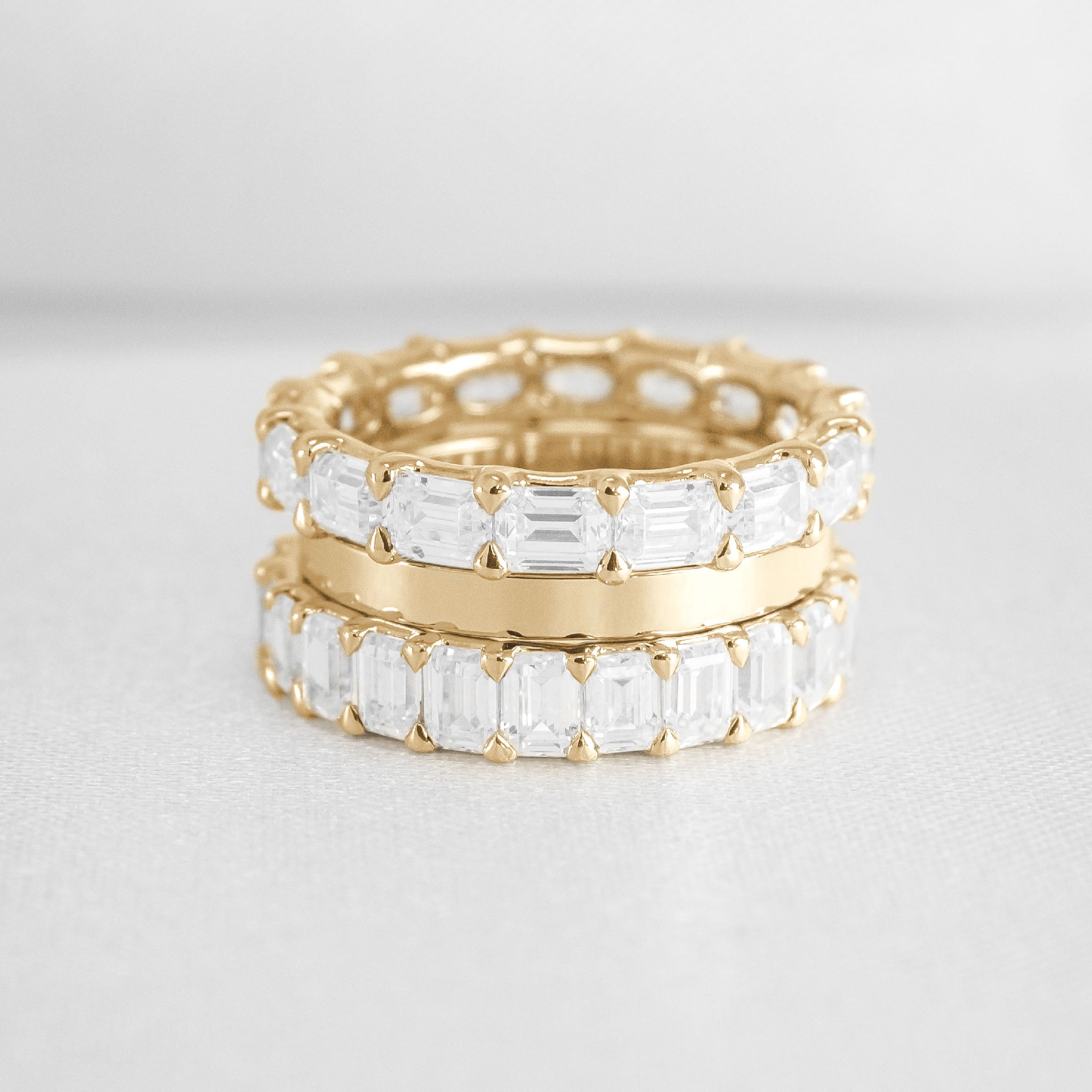 The Ensemble Ring Stack Set comprised of the Avery East West Emerald Cut Eternity Diamond Wedding Ring in 14K yellow gold with Jamie 2mm Wide Flat Wedding Ring in 14K yellow gold and Aniston Emerald Cut Diamond Eternity Wedding Ring in 14K yellow gold from top view by Lisa Robin#color_14k-yellow-gold