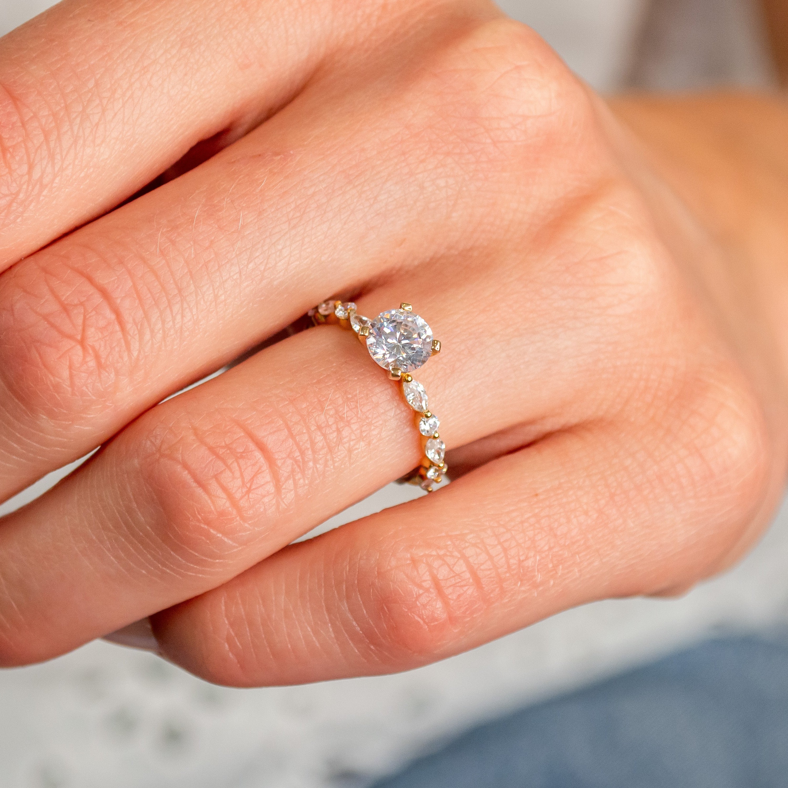 Shown in 1 Carat Diamond*The Marley side stone Engagement Ring with round cut diamond in yellow gold on model hand by Lisa Robin#color_14k-yellow-gold