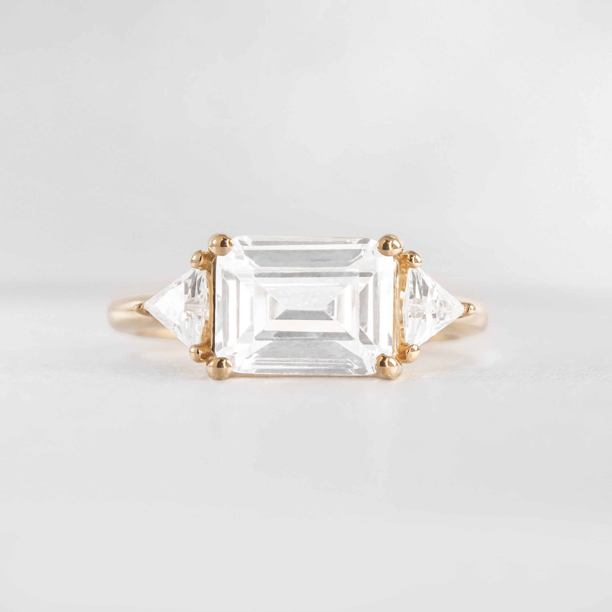 Shown in 3 Carat Diamond*The Sloane East-West Three Stone Engagement Ring with emerald cut diamond in yellow gold from front by Lisa Robin#color_14k-yellow-gold
