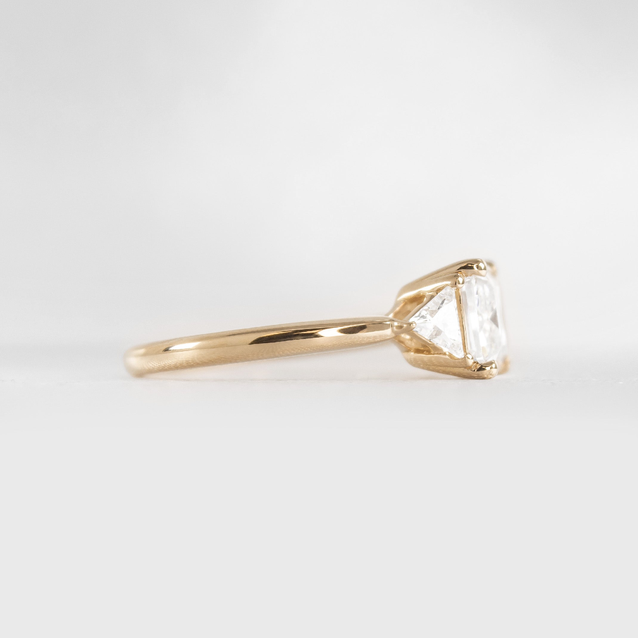 Shown in 3 Carat Diamond*The Sloane East-West Three Stone Engagement Ring with emerald cut diamond in yellow gold from side view by Lisa Robin#color_14k-yellow-gold