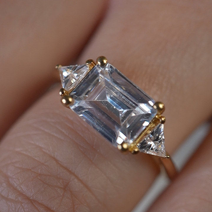 Shown in 3 Carat Diamond*The Sloane East-West Three Stone Engagement Ring with emerald cut diamond in yellow gold on model hand by Lisa Robin#color_14k-yellow-gold