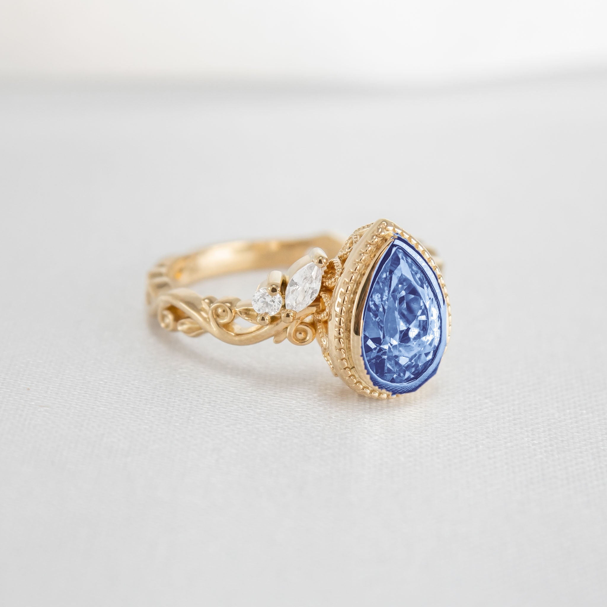 Shown in 2 Carat Blue Diamond*The Fable Symmetry victorian style bezel Engagement Ring with blue pear cut diamond in yellow gold from front angle by Lisa Robin#color_14k-yellow-gold