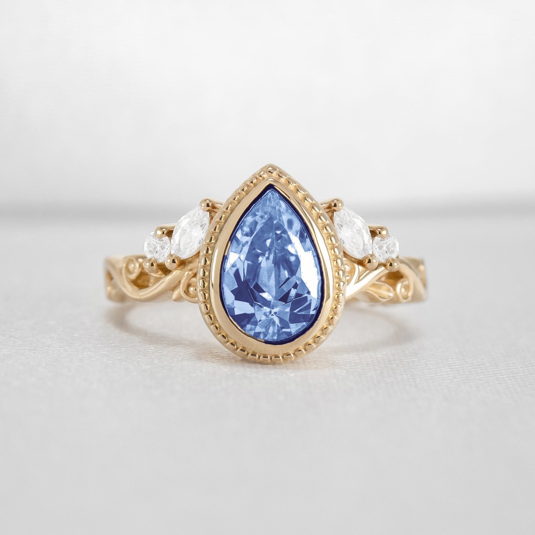 Shown in 2 Carat Blue Diamond*The Fable Symmetry victorian style bezel Engagement Ring with blue pear cut diamond in yellow gold from front by Lisa Robin#color_14k-yellow-gold