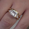 The Sloane East-West Three Stone Engagement Ring with emerald cut diamond in yellow gold paired with the Reese dome Lab Diamond Wedding Ring in 14K yellow gold on model hand by Lisa Robin Jewelry