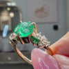 The Chloe Emerald Center and Diamond and Emerald Accent Cluster Engagement Ring held in fingers | Lisa Robin