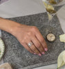 Anna round diamond cluster engagement ring in yellow gold with Kendal and Marla curved diamond wedding rings on model by Lisa Robin